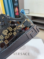 Black Versace high-top sneakers with gold Greca logos and chunky gray platform sole