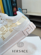 Versace white sneakers with Greek-key panel and blue logo heel detail, side view close-up.