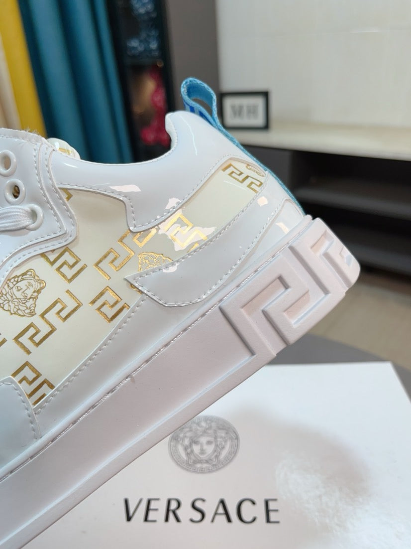 Versace white sneakers with Greek-key panel and blue logo heel detail, side view close-up.
