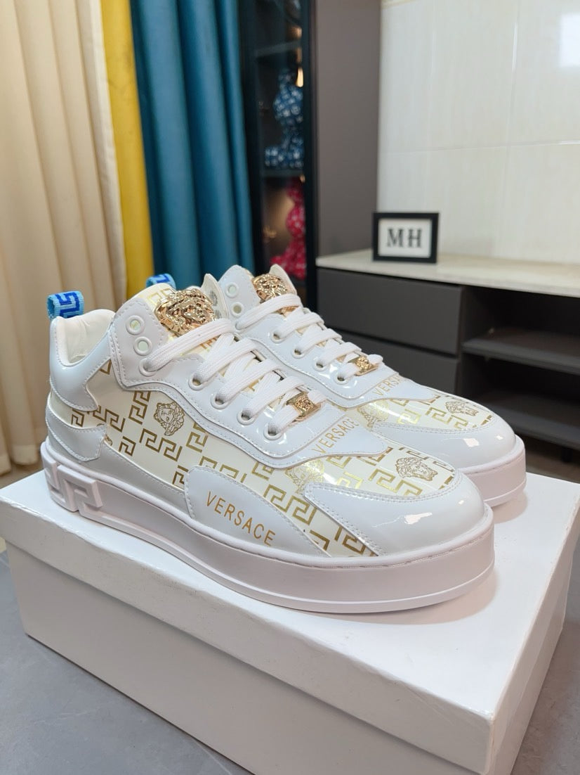 Versace white lace-up sneakers with gold crest and Greek-key pattern, chunky platform sole.