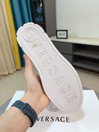 Versace white sneaker outsole with embossed VERSACE lettering, held by the heel.