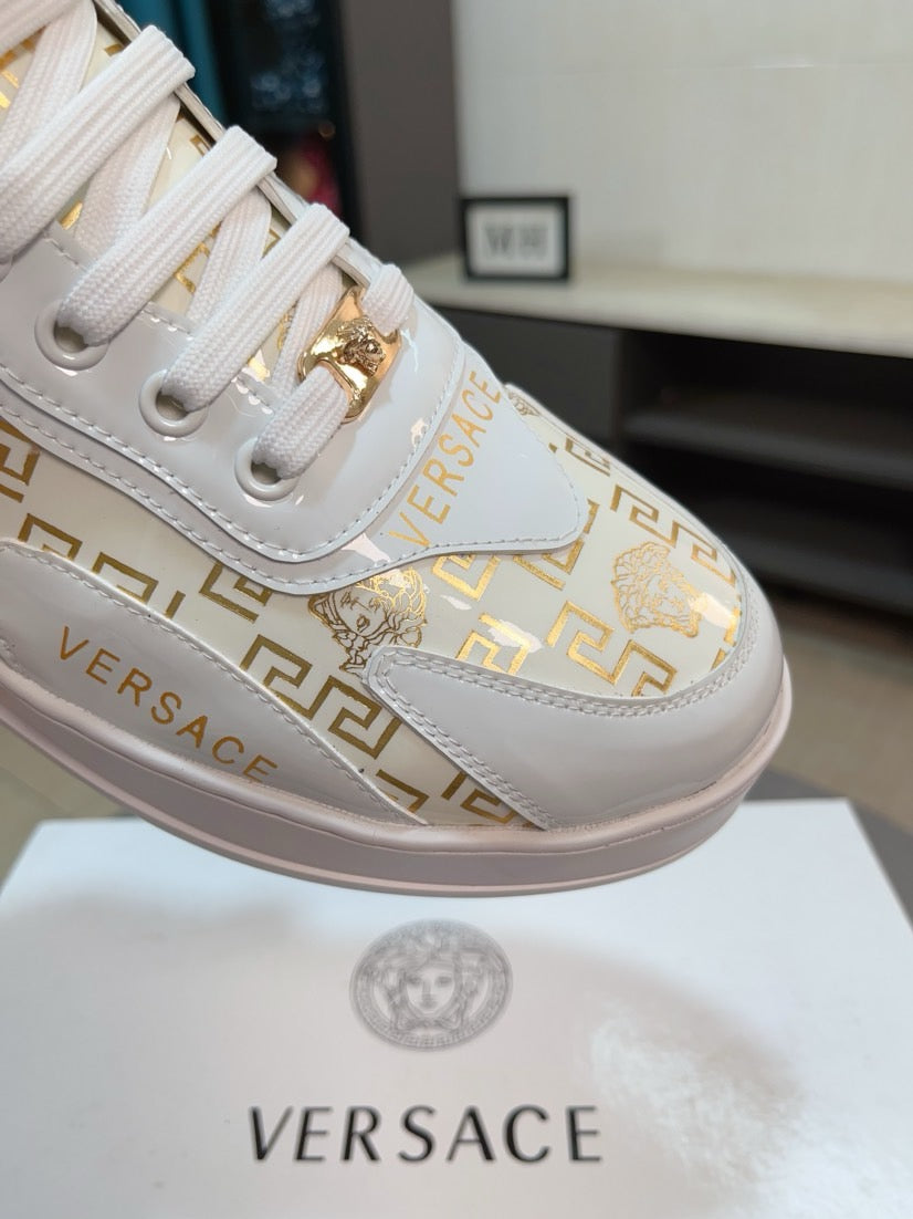Versace white leather sneakers with gold and Greca logos, lace area close-up detail.