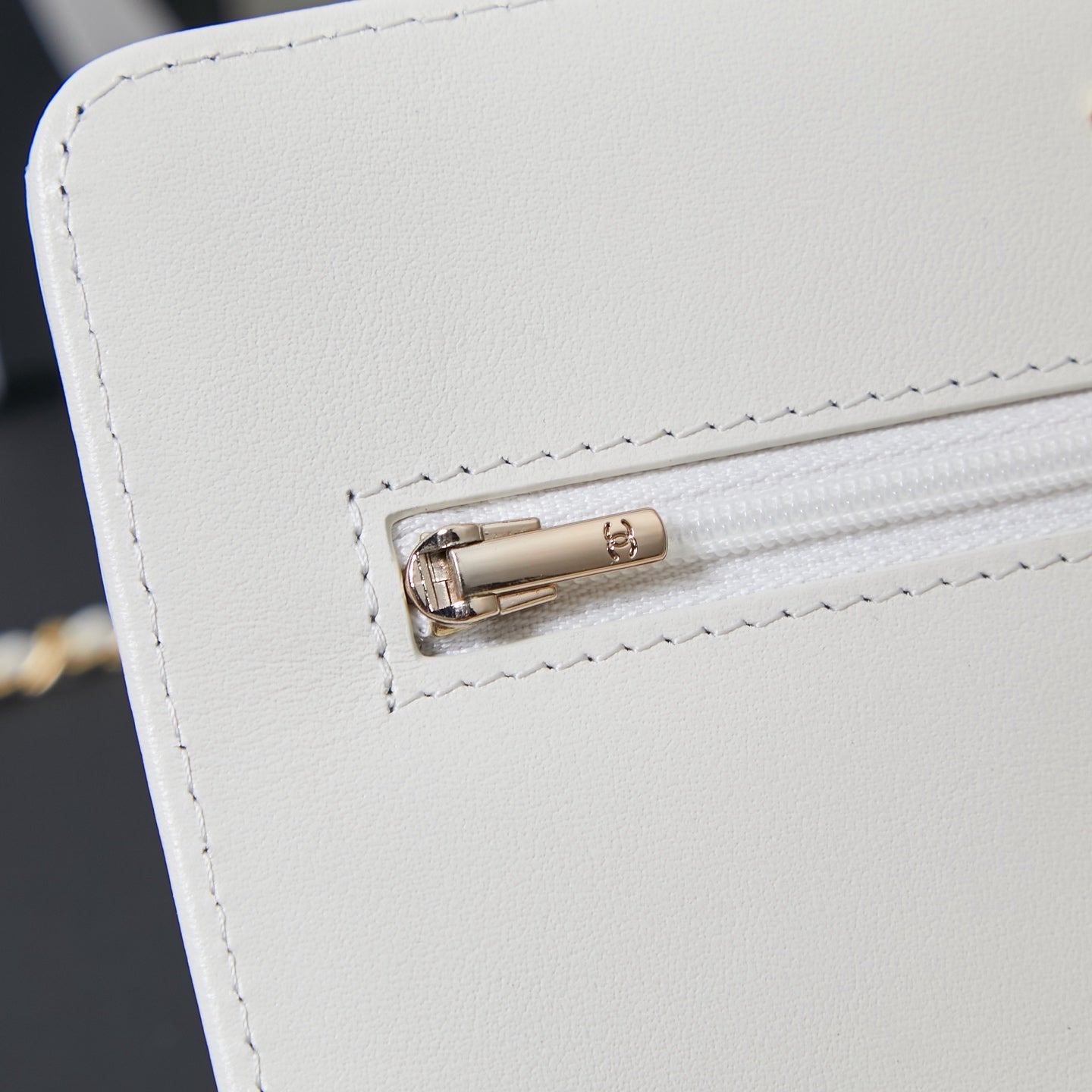 White Chanel bag close-up of gold-tone turn-lock clasp on front flap