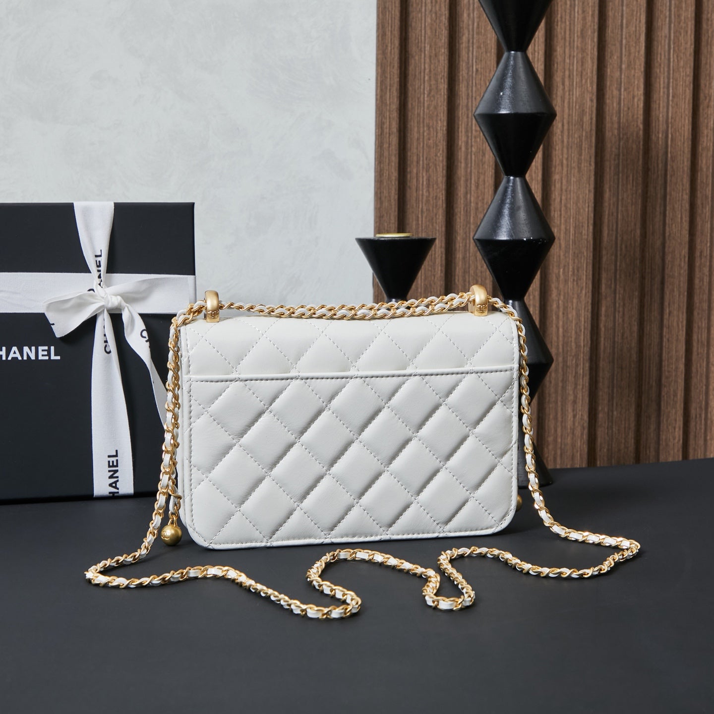 White quilted Chanel crossbody bag with gold chain strap draped across front
