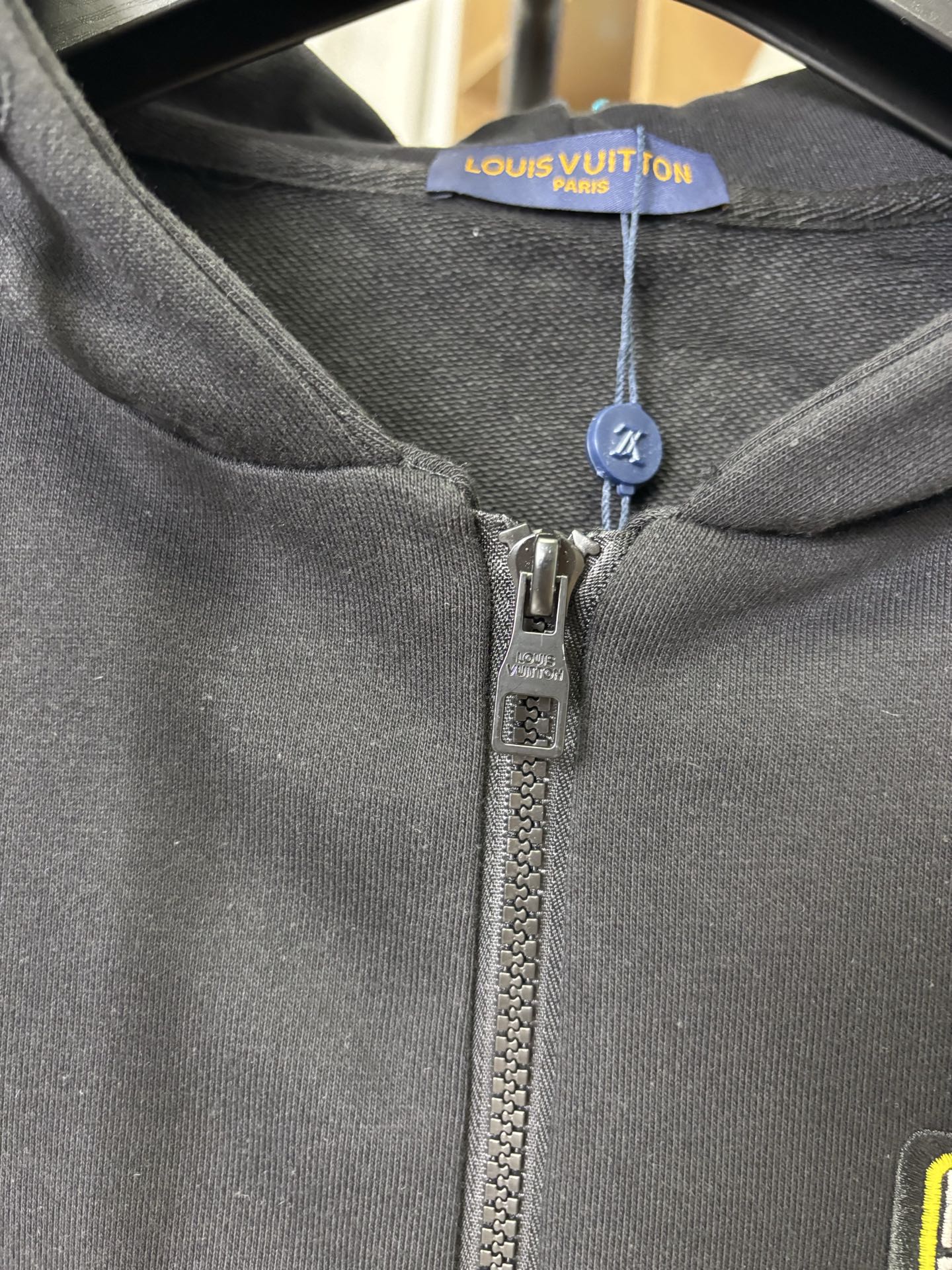 Black zip-up hoodie neckline with Louis Vuitton label and metal zipper pull