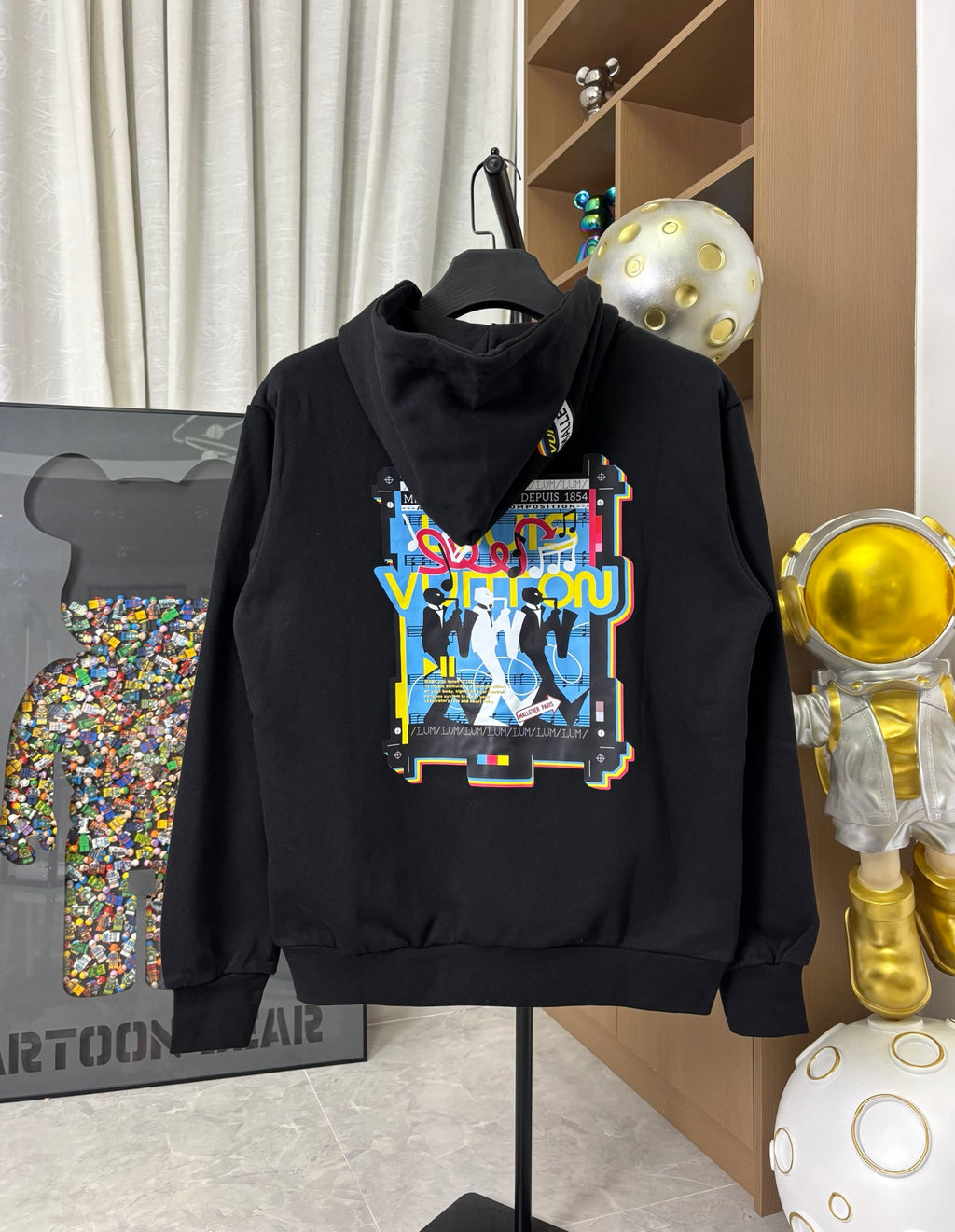Black zip-up hoodie with multicolor graphic patch and hood drawstrings