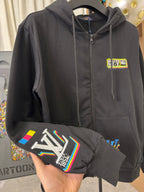 Black zip-up hoodie with chest badge and colorful graphic on sleeve