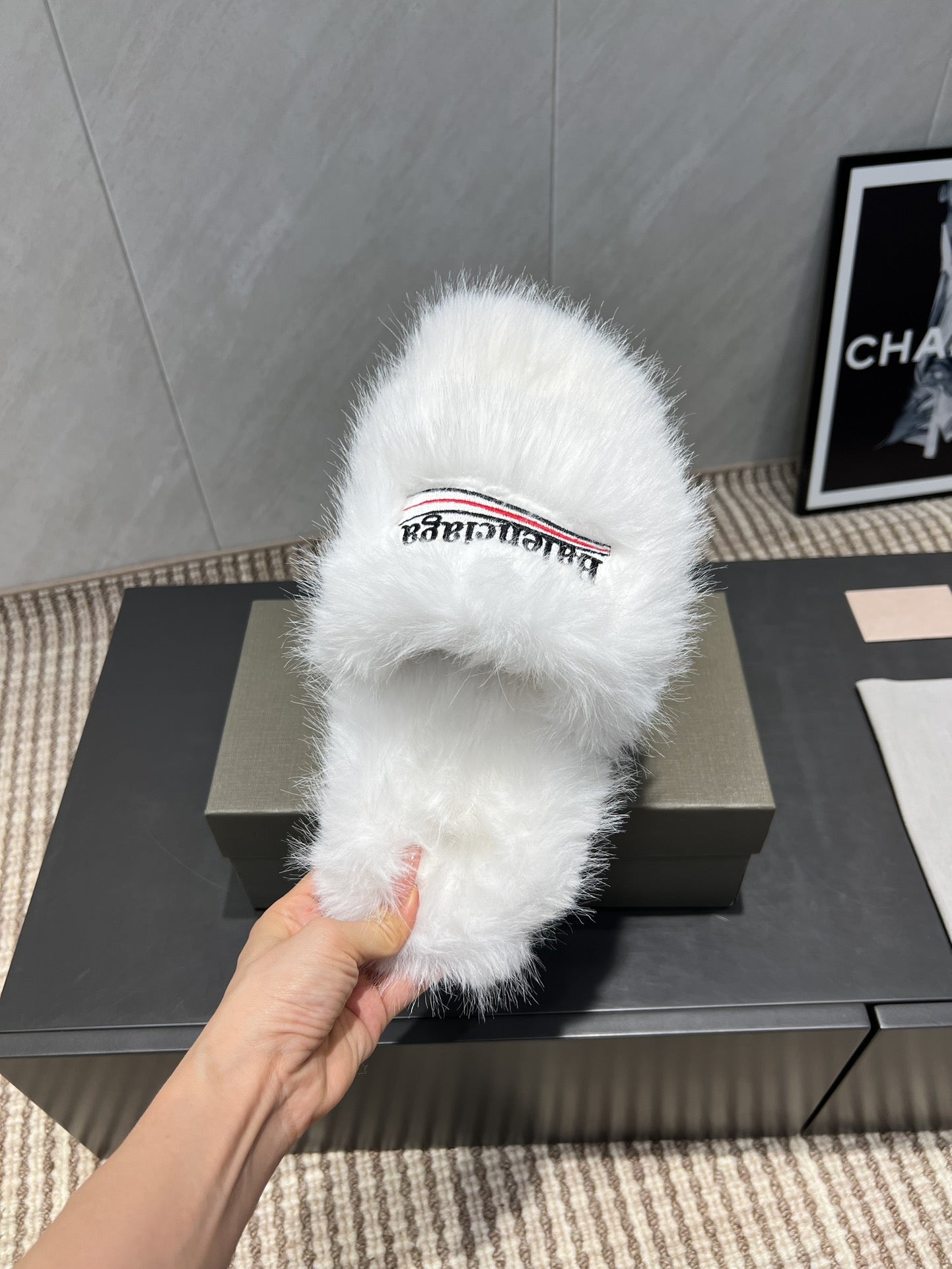 White fur slide sandal on box, hand holding front