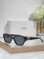 Black cat-eye sunglasses with gold logo detail and blue-tinted lenses on front view