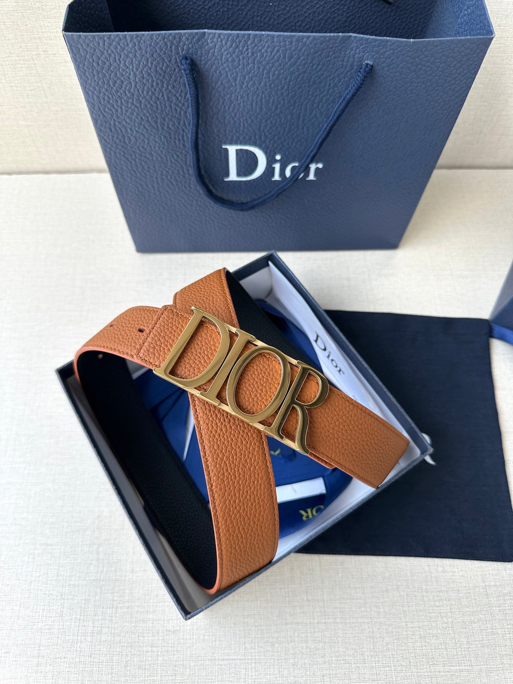 Tan leather Dior belt with wide buckle and smooth strap in blue box.