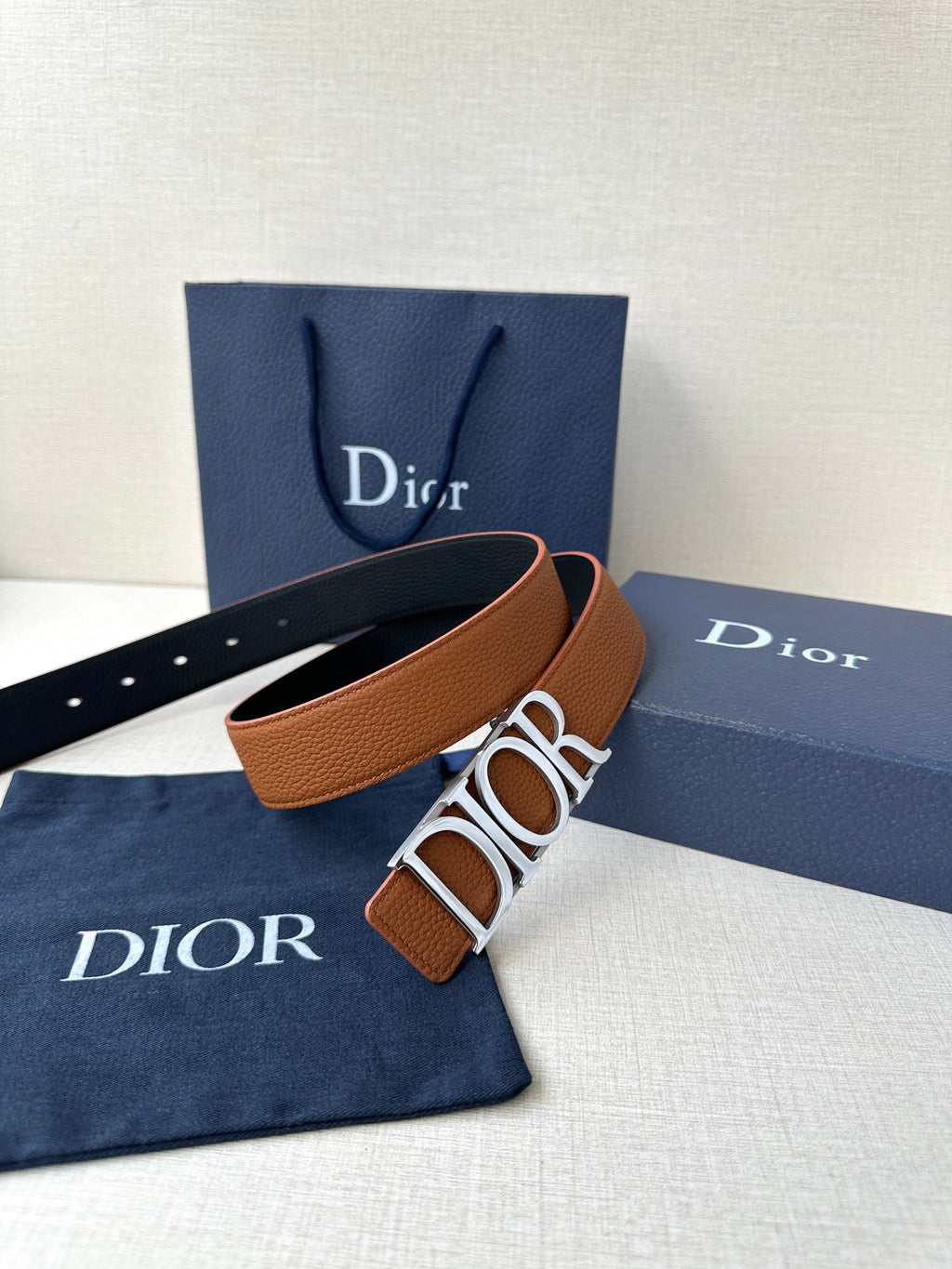 Tan leather Dior belt with large engraved buckle and perforated strap holes.