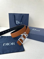 Tan leather Dior belt with large engraved buckle and perforated strap holes.