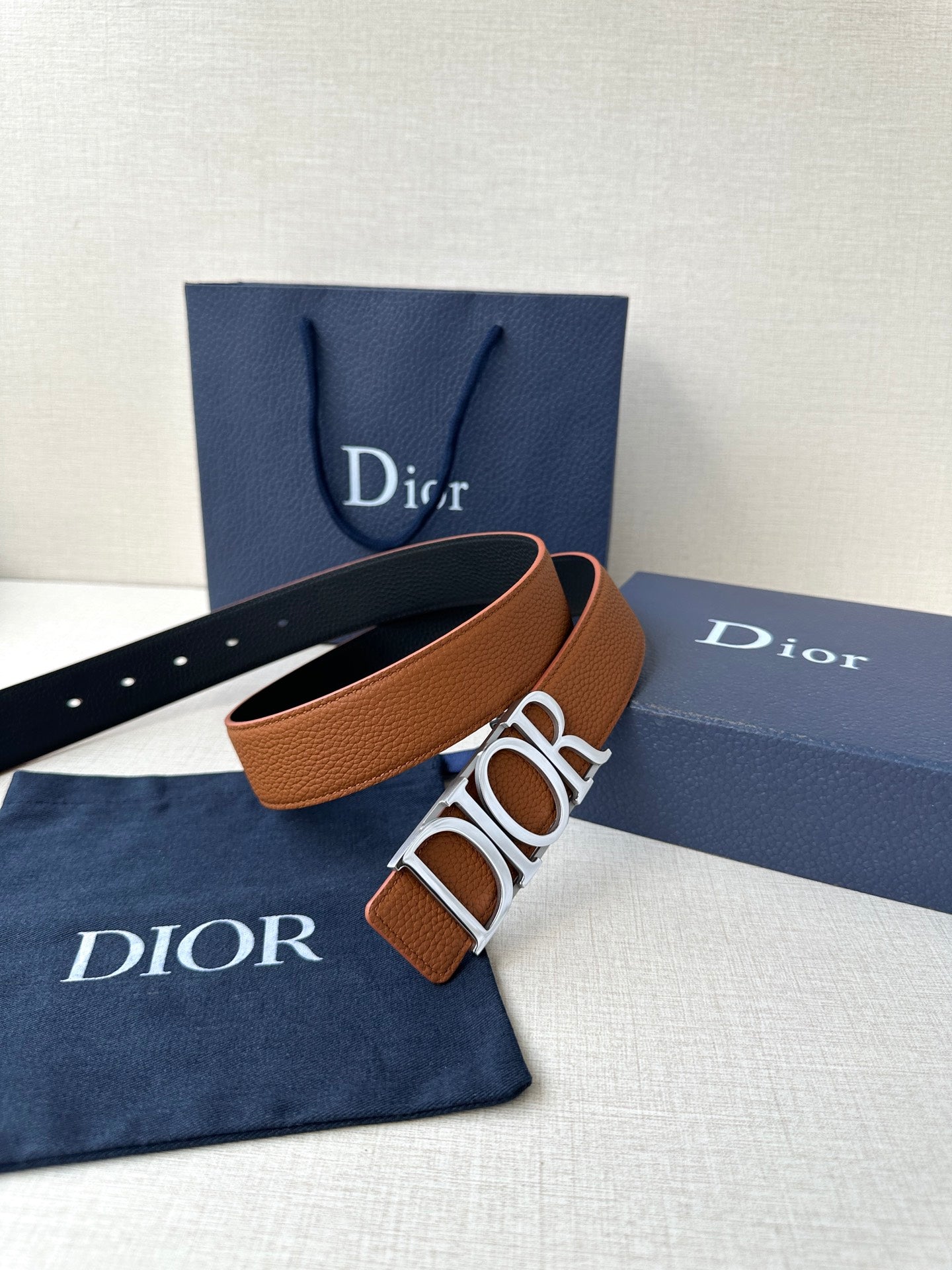 Tan leather Dior belt with large engraved buckle and perforated strap holes.