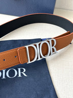 Tan and black Dior belt buckle detail with embossed letter logo on strap.