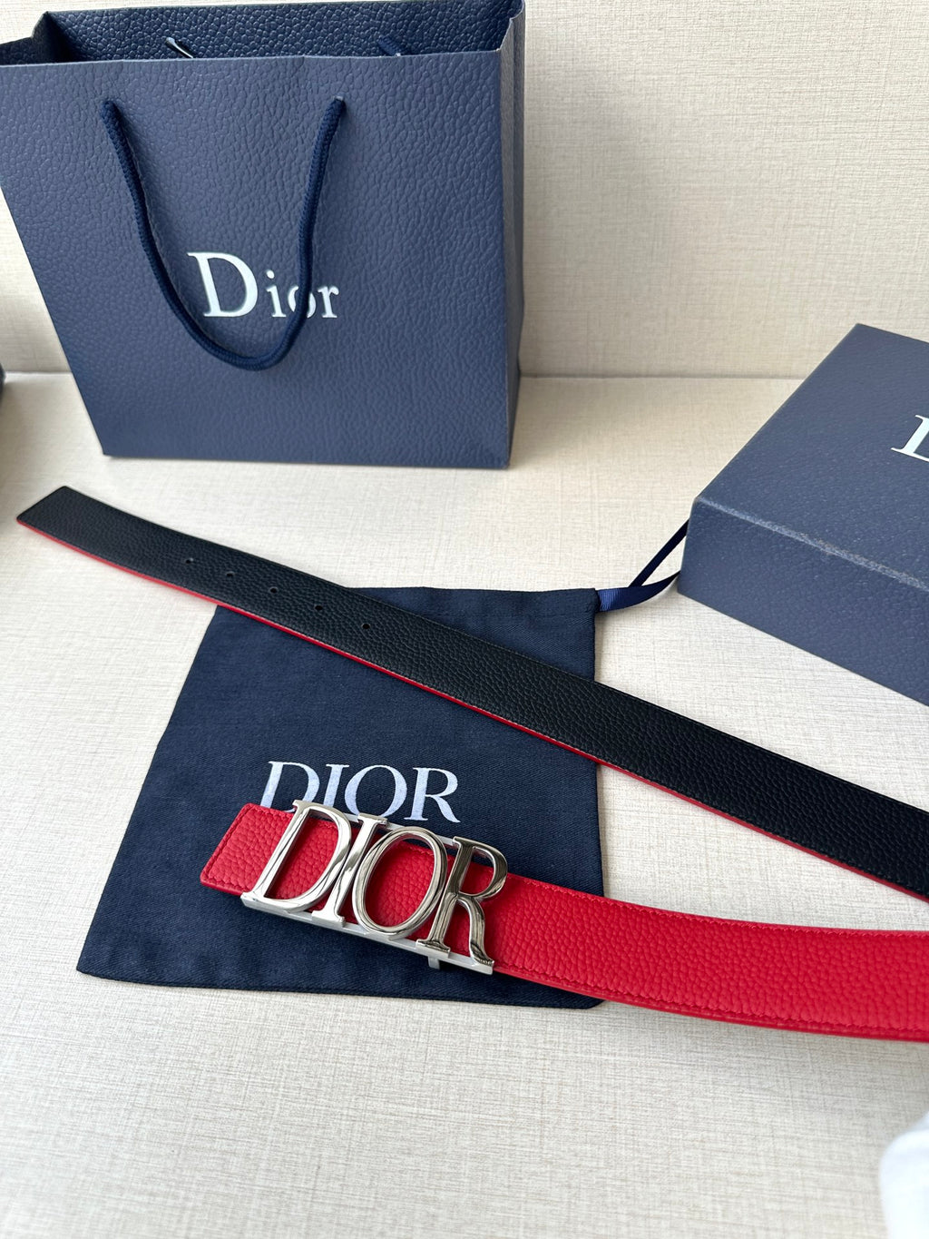 Dior red leather belt laid flat with gold-tone “DIOR” buckle