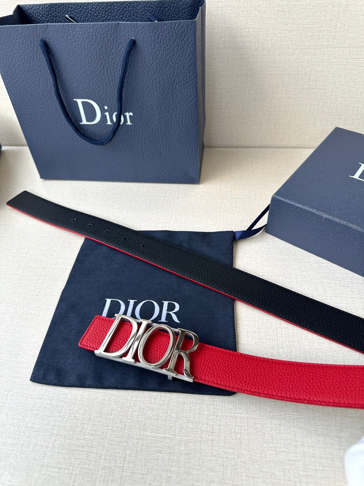 Dior red leather belt laid flat with gold-tone “DIOR” buckle
