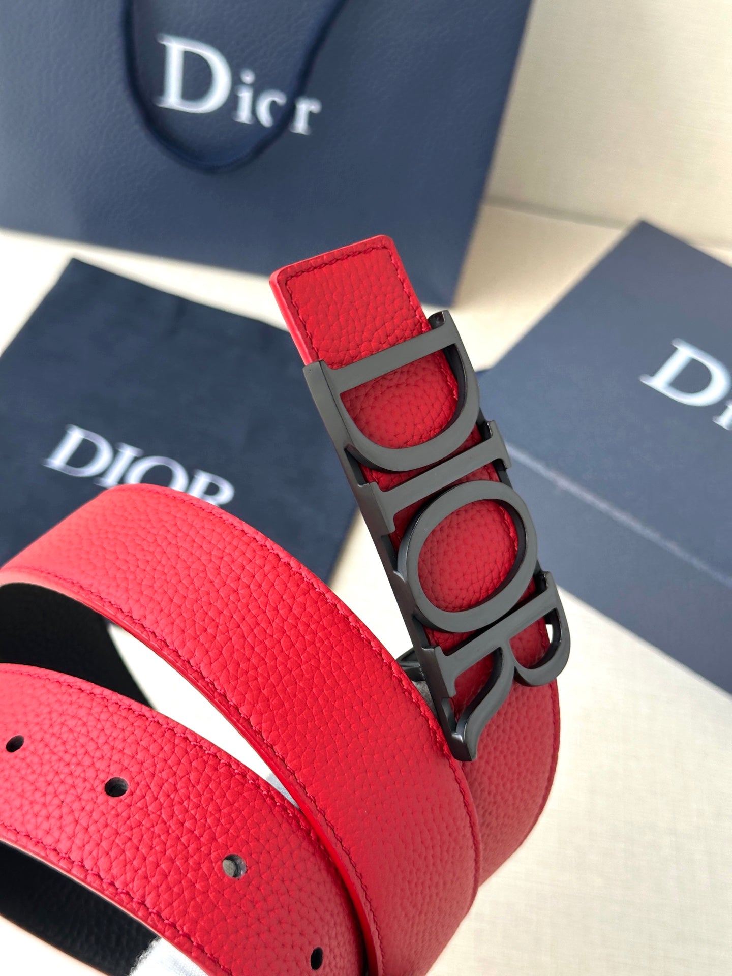 Dior belt detail: red strap with decorative buckle and punched holes
