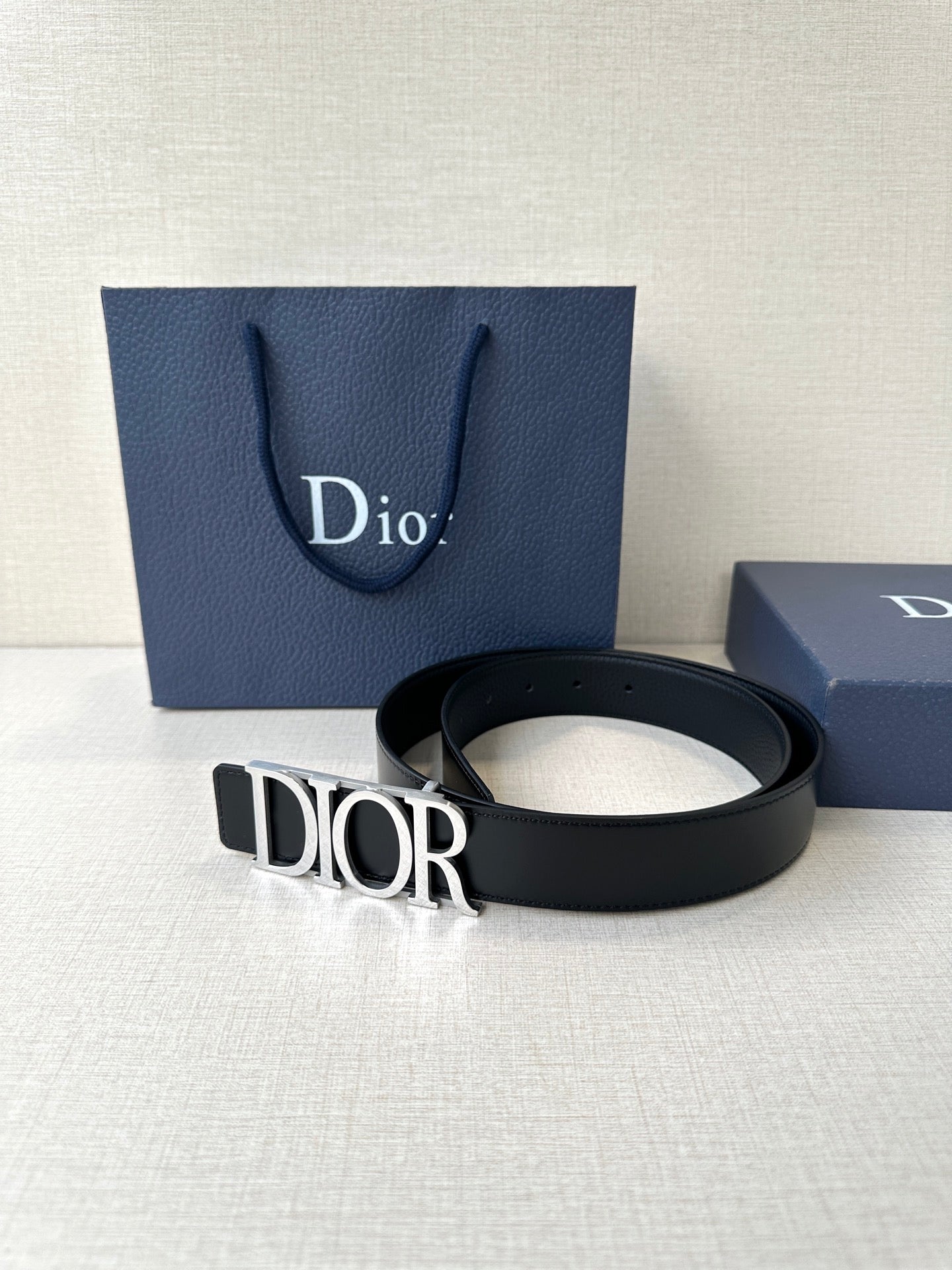 Black leather Dior belt with engraved Dior buckle, strap coiled