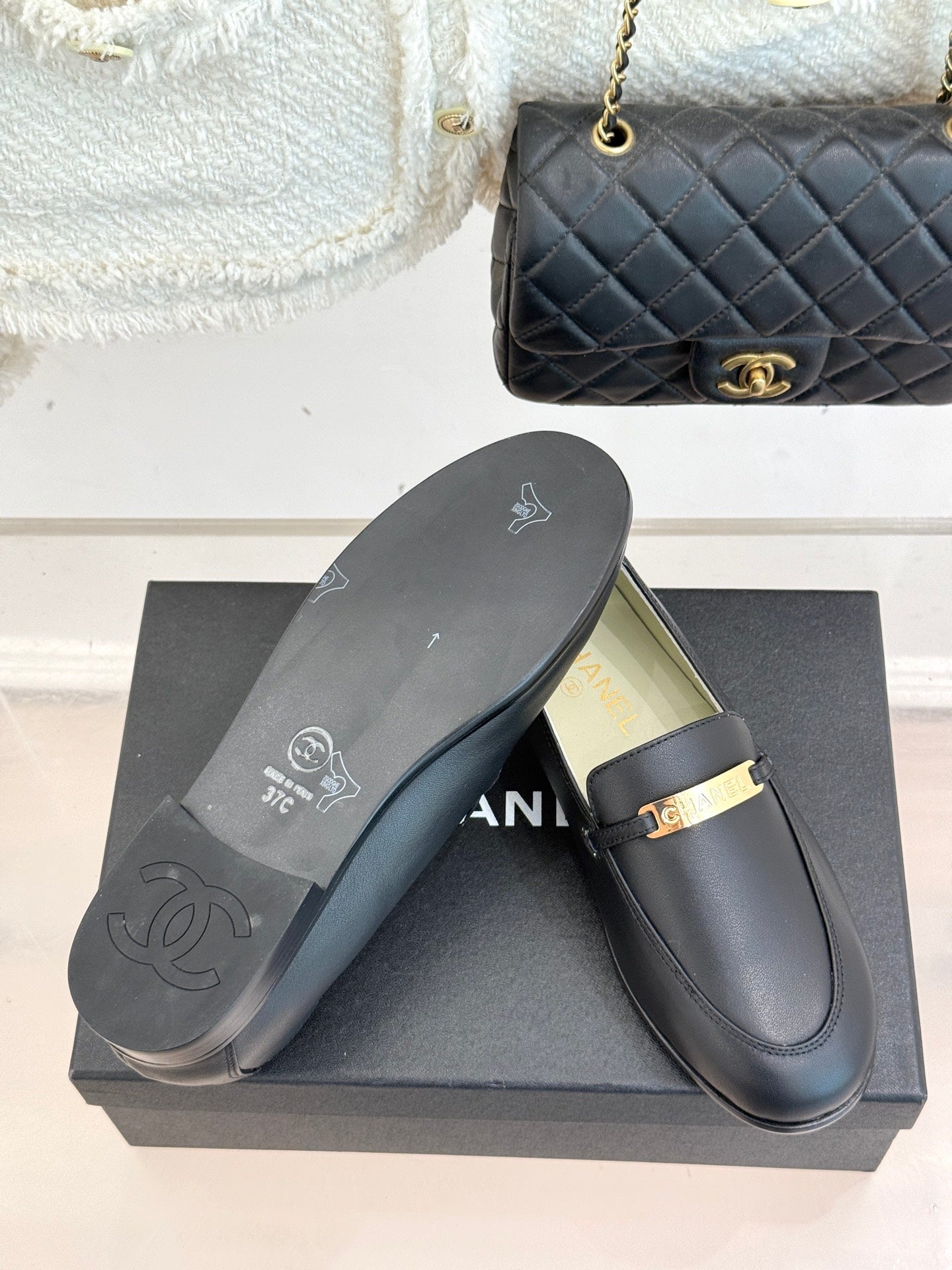 Black leather loafers with flat rubber sole and gold buckle bar, Chanel