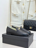 Black leather loafer flats with gold buckle bar and Chanel logo detail