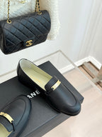 Black leather slip-on loafers with gold buckle bar strap and Chanel logo