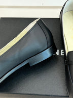 Close-up black leather loafer with gold-trimmed strap and low stacked heel