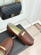 Women’s brown leather loafers with gold buckle bar, angled view