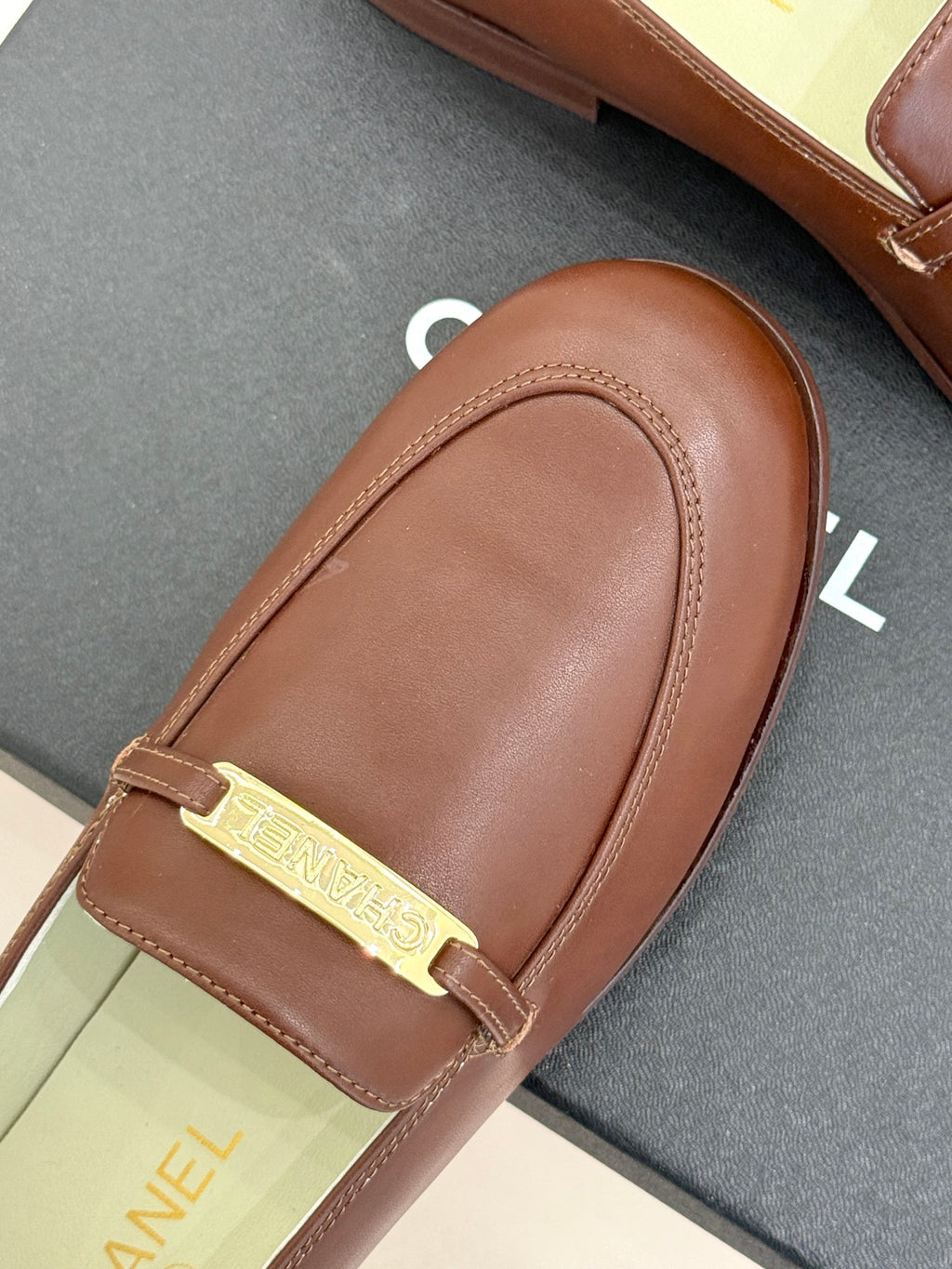Women’s brown leather loafer with gold buckle bar and seam details