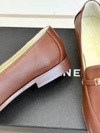 Women’s brown leather loafer with gold buckle bar and stitched apron toe
