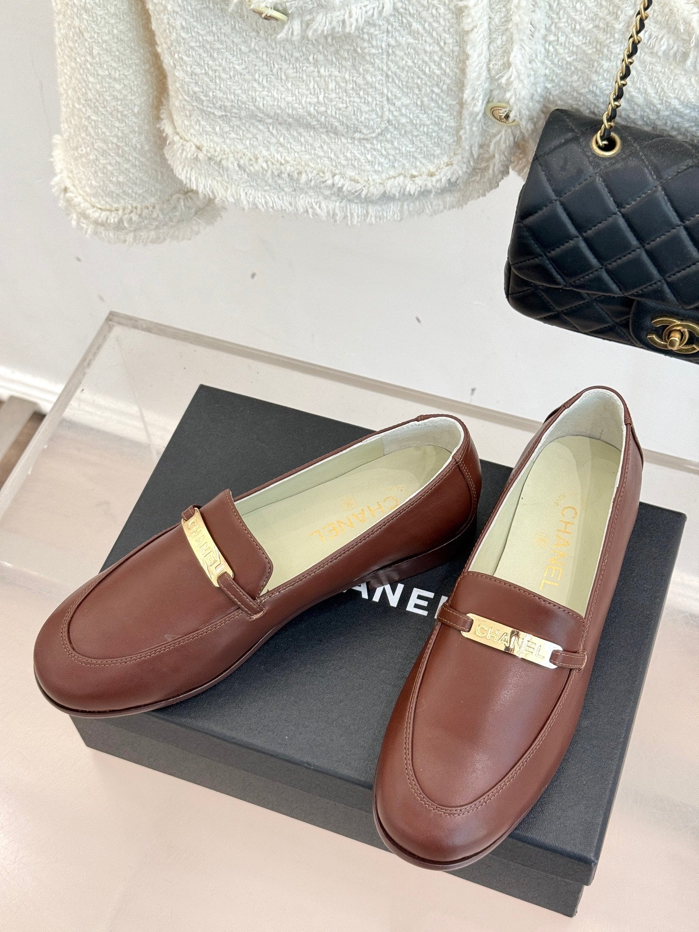 Women’s brown leather loafers with gold bar buckle, shown as a pair