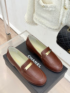 Women’s brown leather loafers with gold buckle strap, front view pair