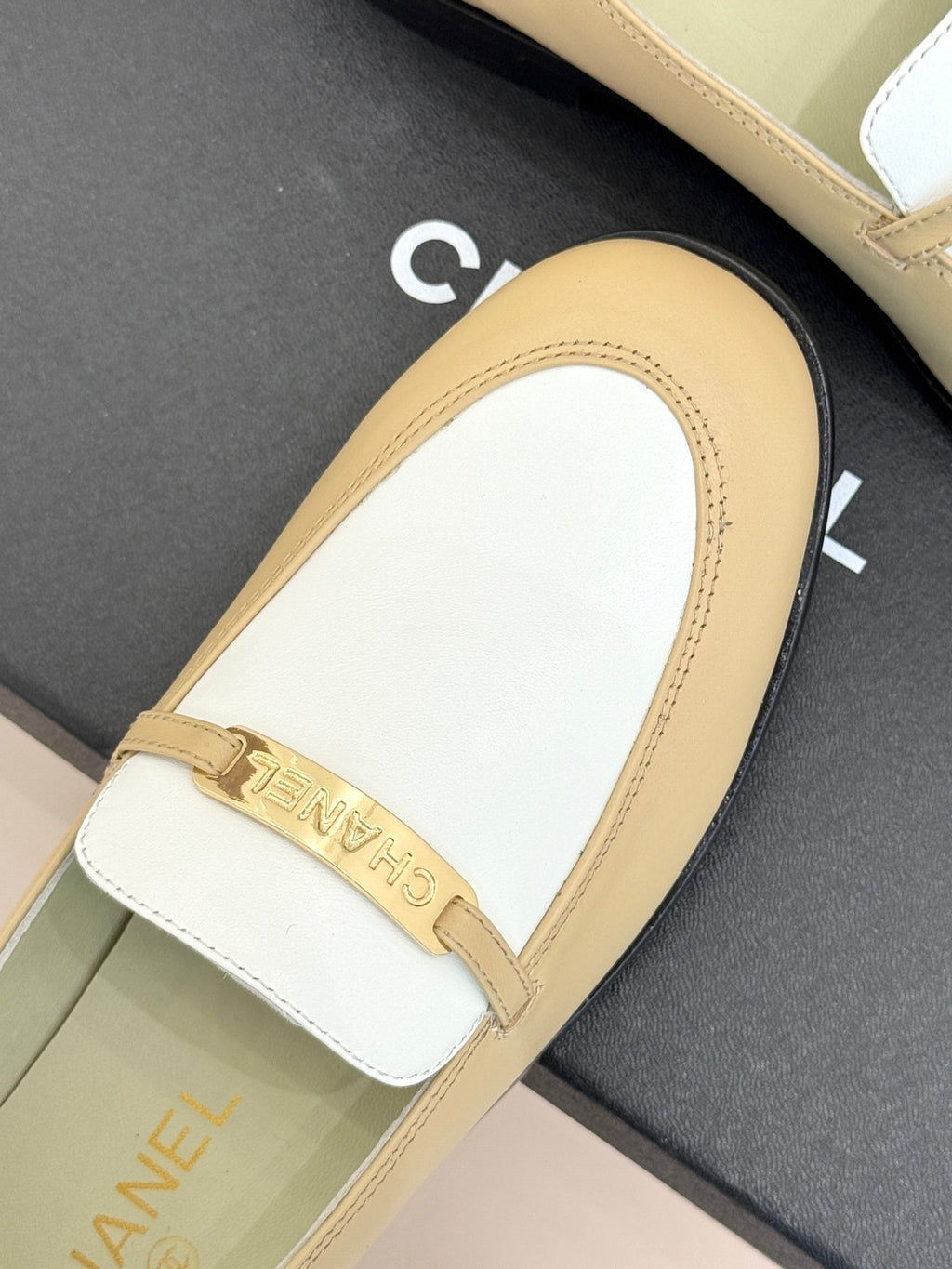 Chanel women's loafer close-up, white vamp with cream border and gold buckle