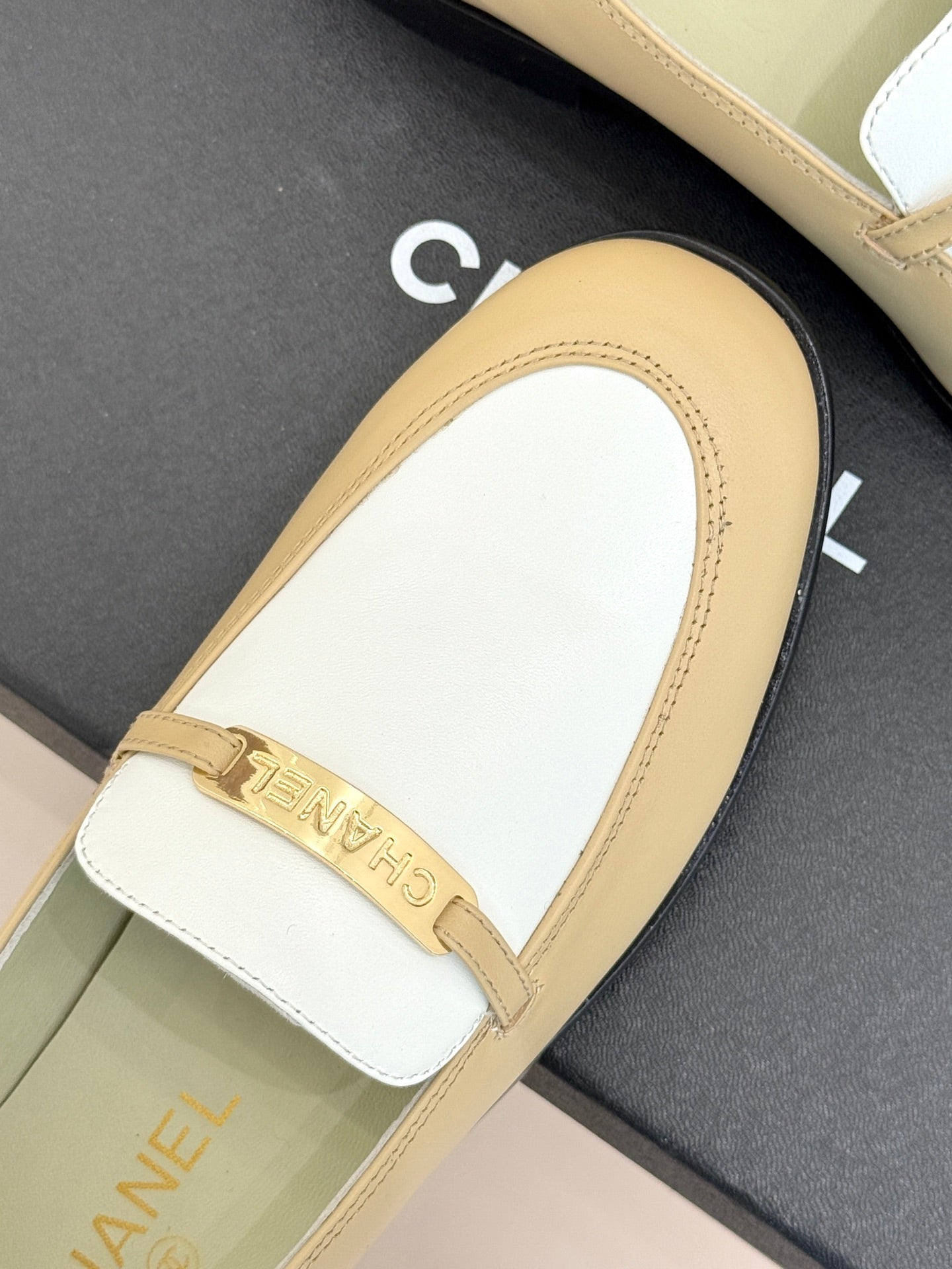 Chanel women's loafer close-up, white vamp with cream border and gold buckle