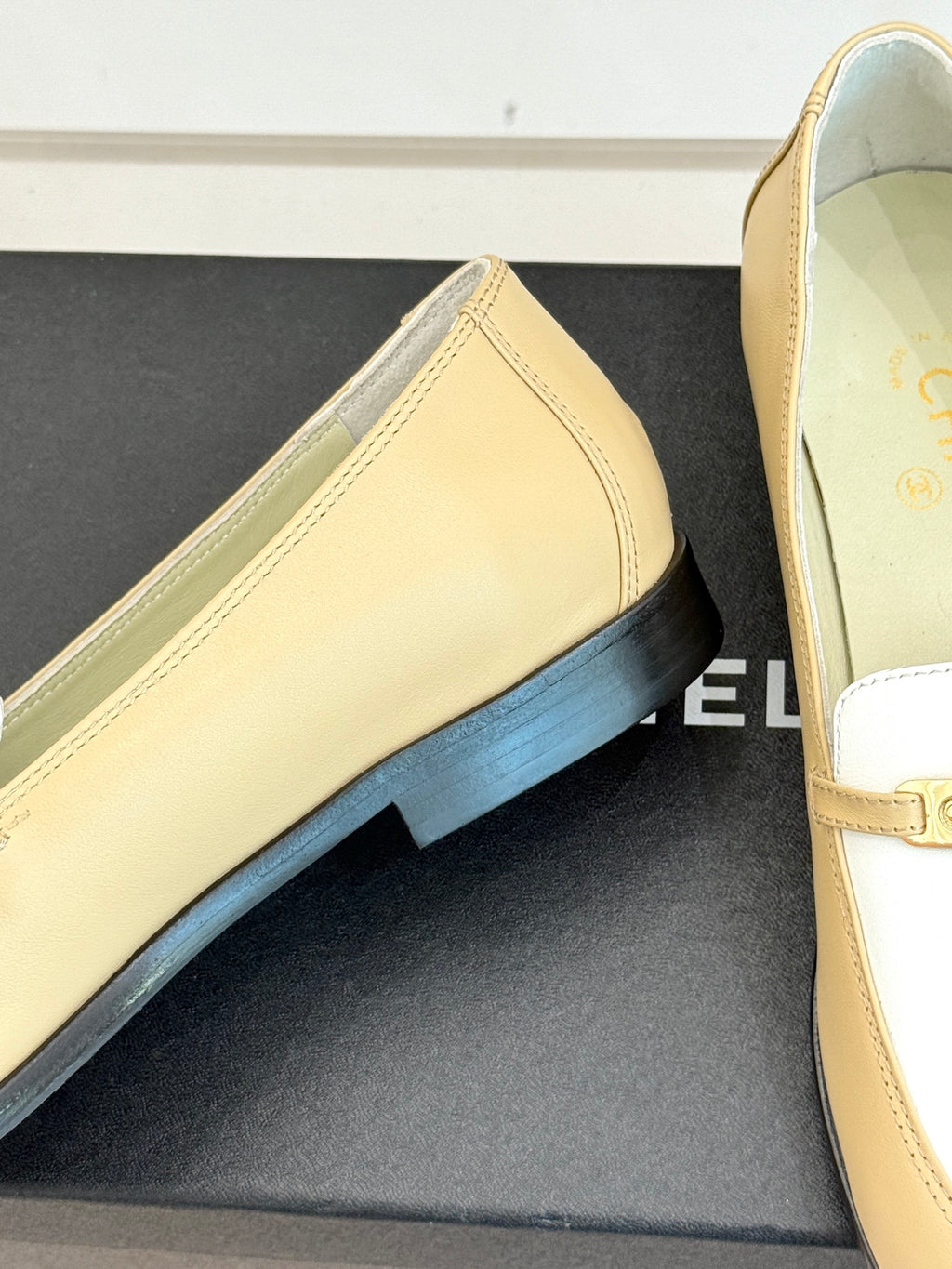 Chanel women's loafer close-up, cream leather with white strap and gold buckle