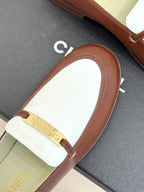 Chanel ladies luxury loafer close-up, brown leather toe with white strap and gold bar