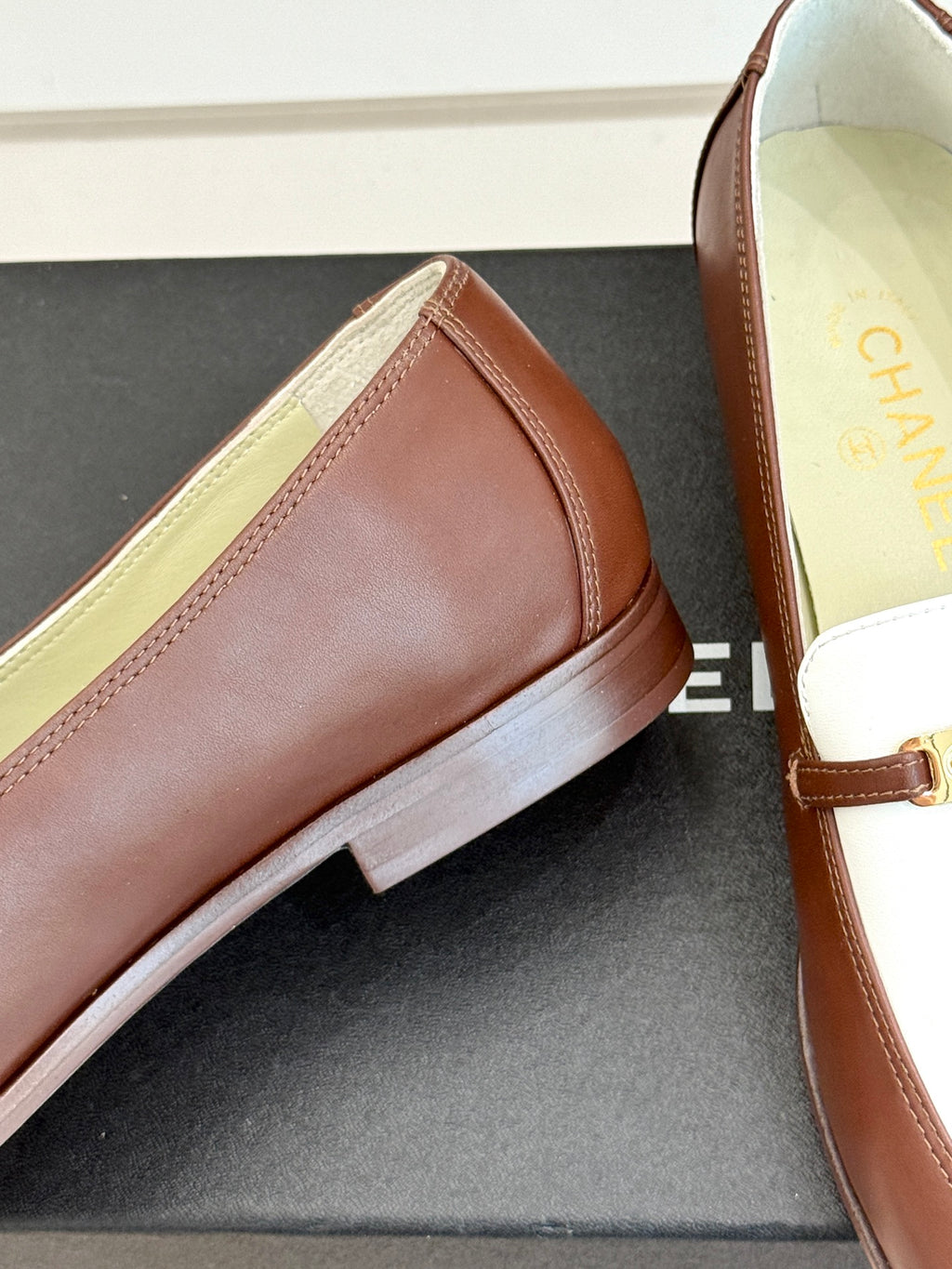 Chanel ladies luxury loafer side view, brown leather with white strap and gold trim