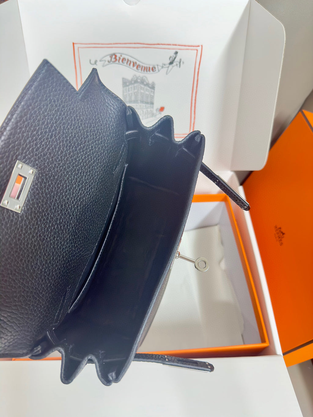 Hermes handbag in dark textured leather, back view showing side strap and interior.