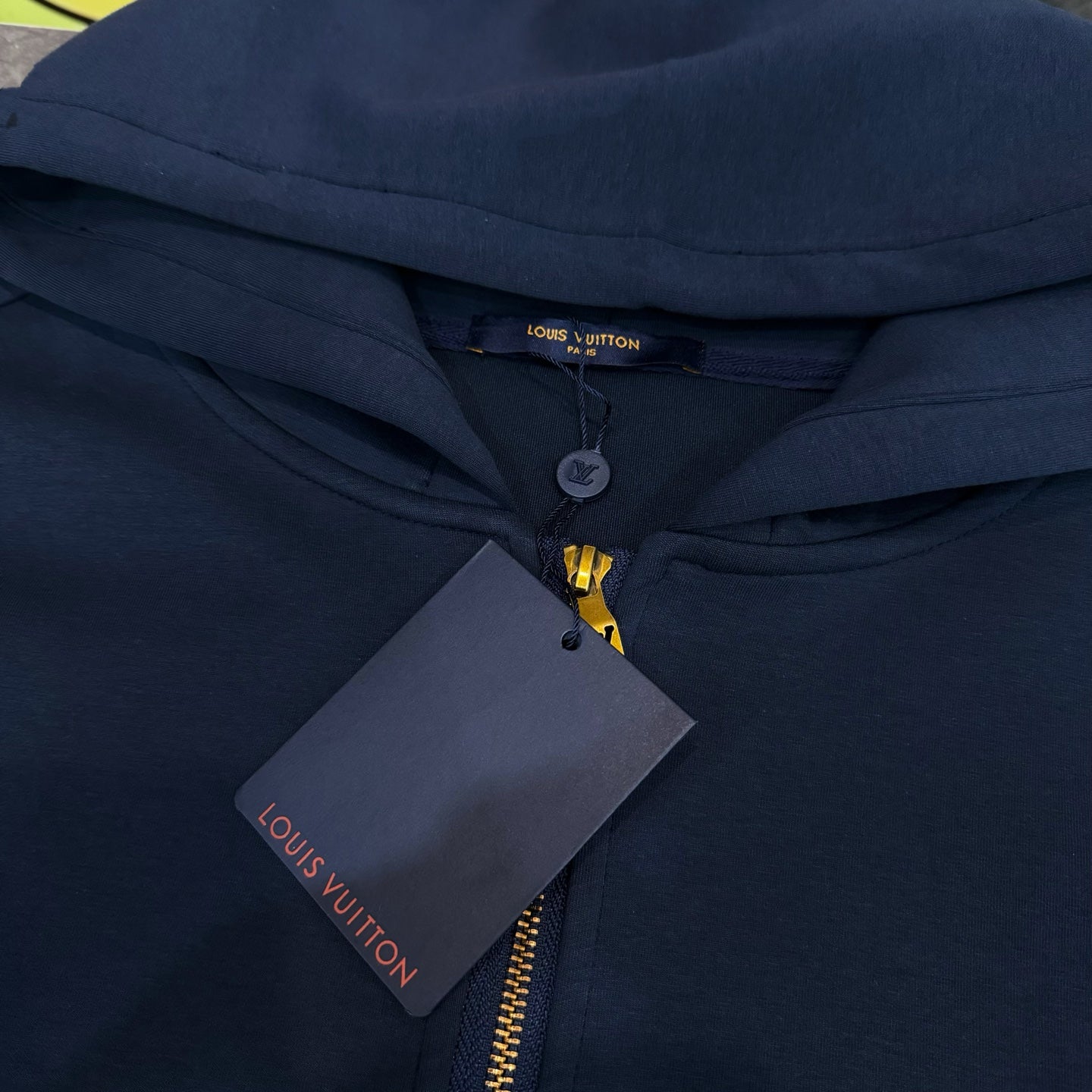 Navy Louis Vuitton hoodie with hood, gold zipper, and hanging price tag