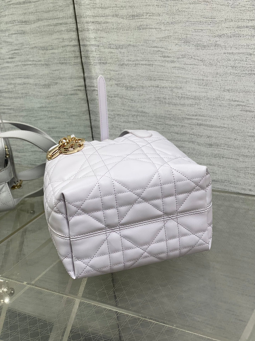 Dior quilted mini handbag side view with gold clasp and structured light white body