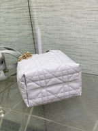Dior quilted mini handbag side view with gold clasp and structured light white body