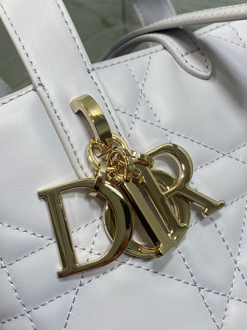 Dior bag close-up: gold tone Dior hardware on quilted light white leather