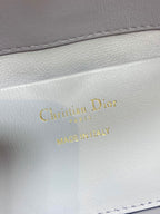 Dior bag close-up of "Christian Dior" and "MADE IN ITALY" stamping on light white leather
