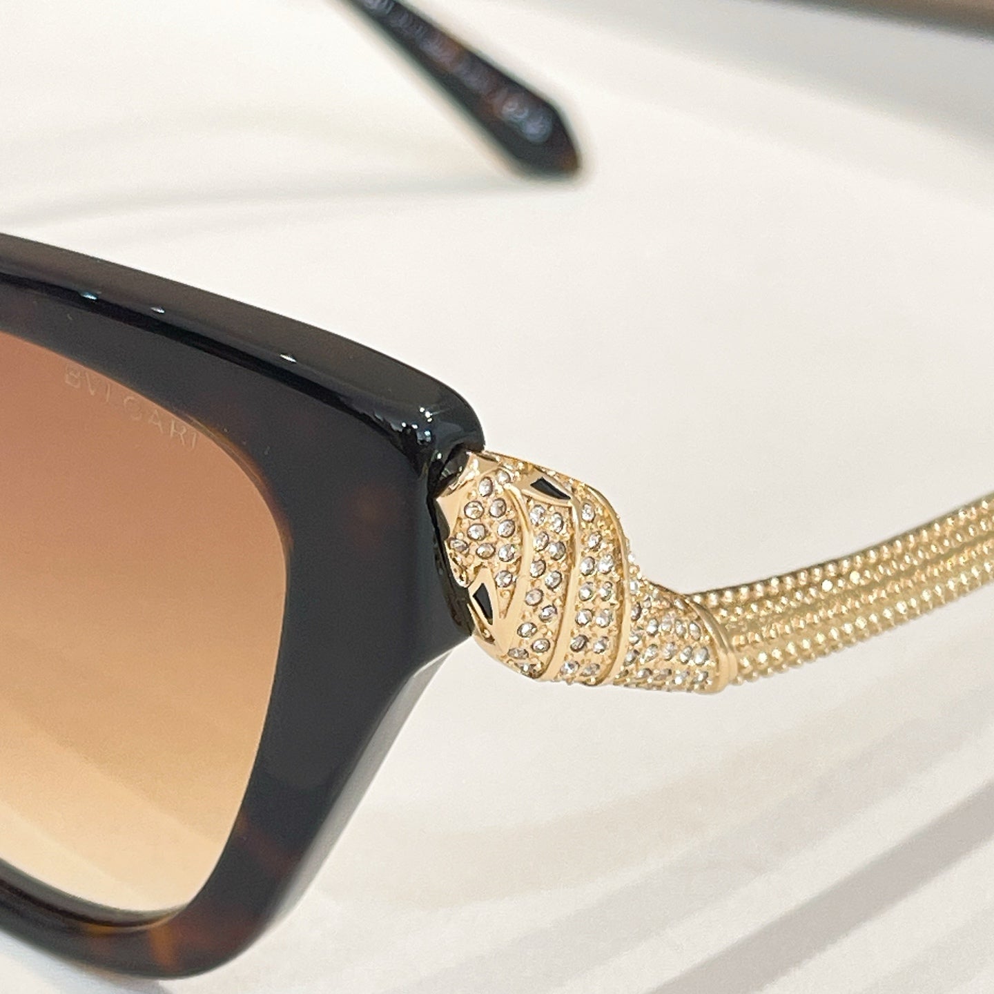 Bvlgari sunglasses with glossy dark frame and gold rhinestone temple detail