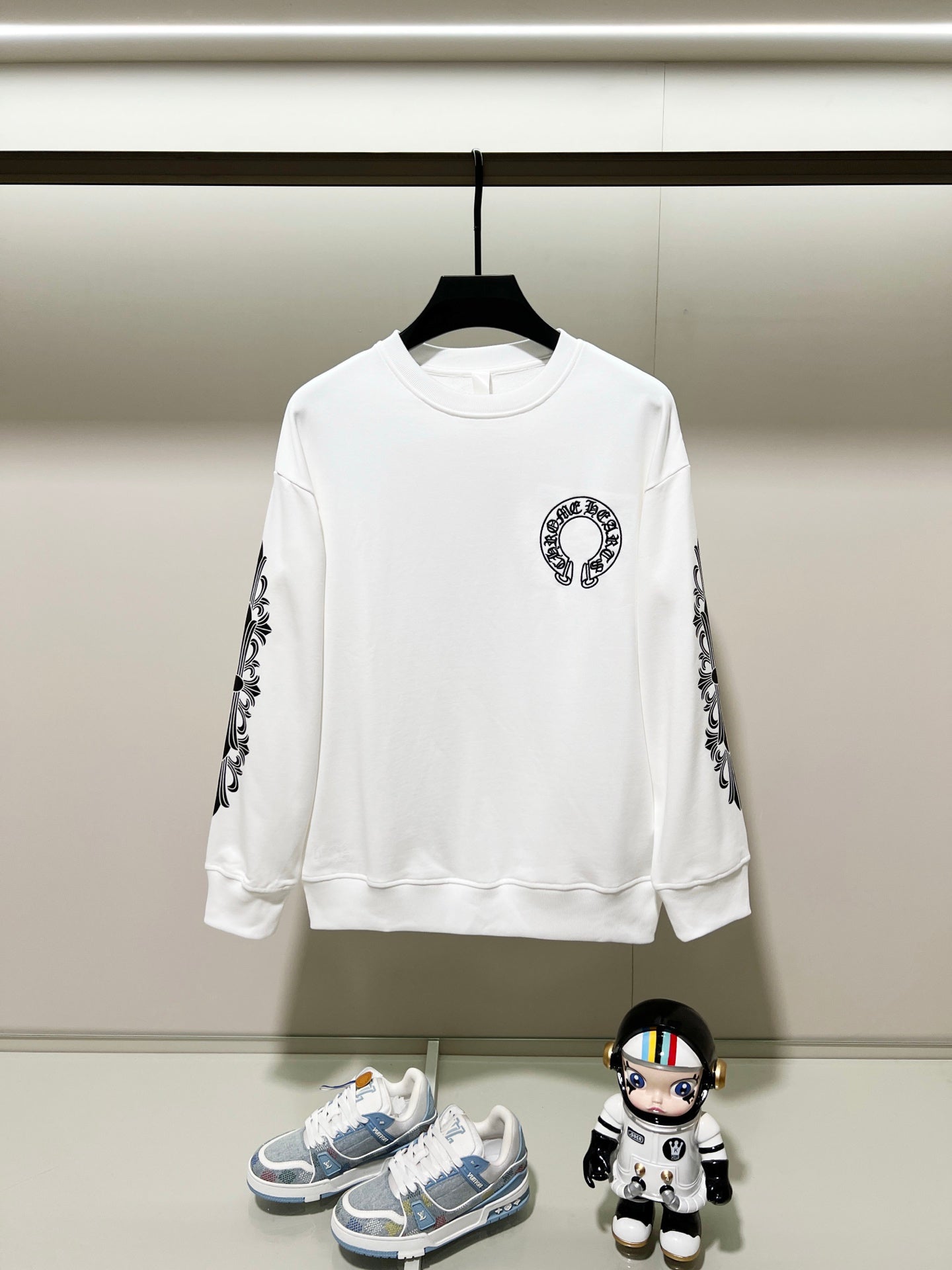 White long-sleeve crewneck sweatshirt with black logo graphic and patterned sleeves