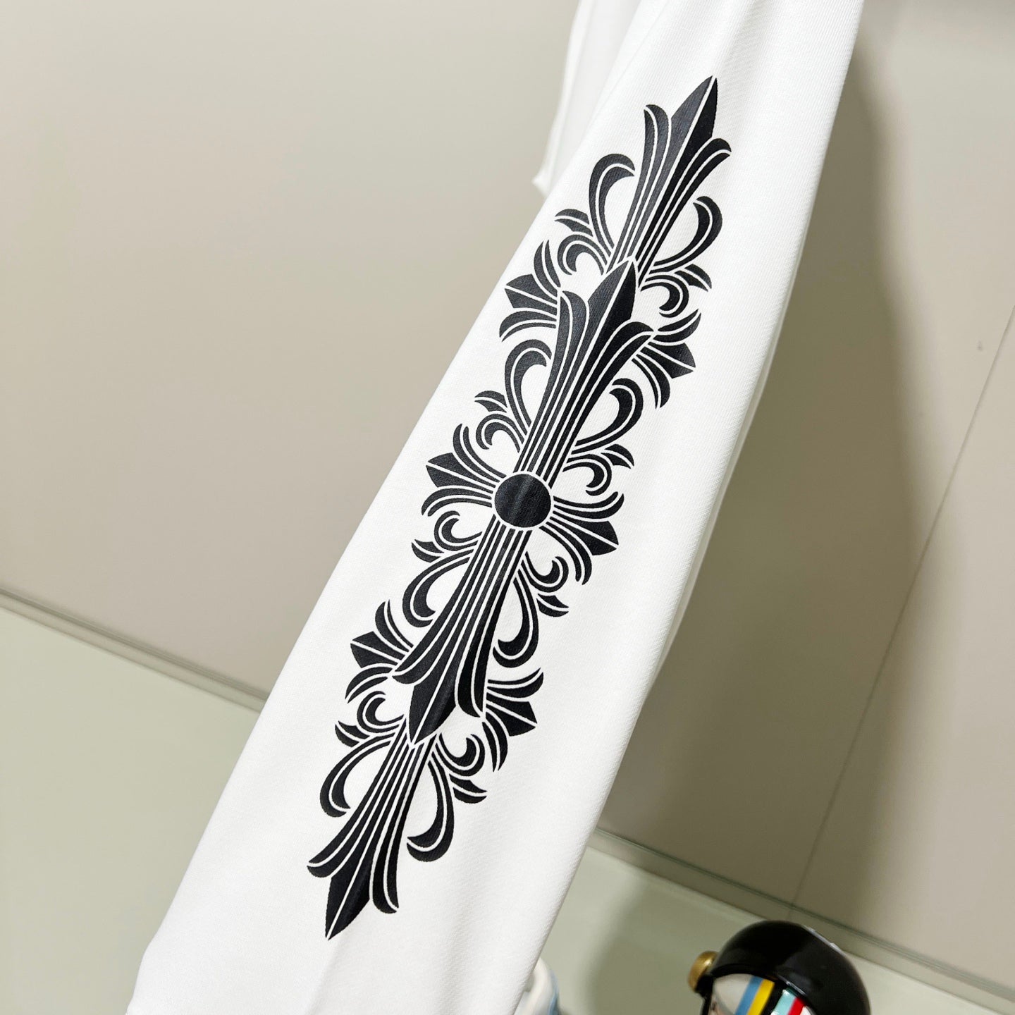 White sweatshirt sleeve with large black decorative floral line art