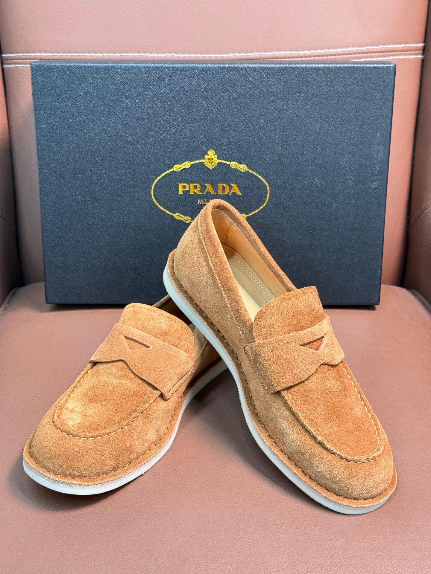 Prada unisex tan suede loafers, side and heel views with white rubber soles.