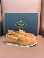 Prada unisex tan suede loafers with white rubber soles, shown in gift box.