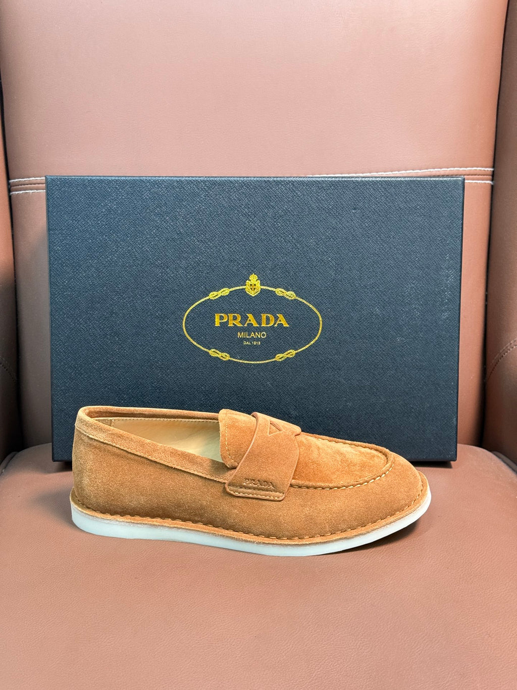 Prada unisex tan suede loafer with white rubber sole, boxed presentation.