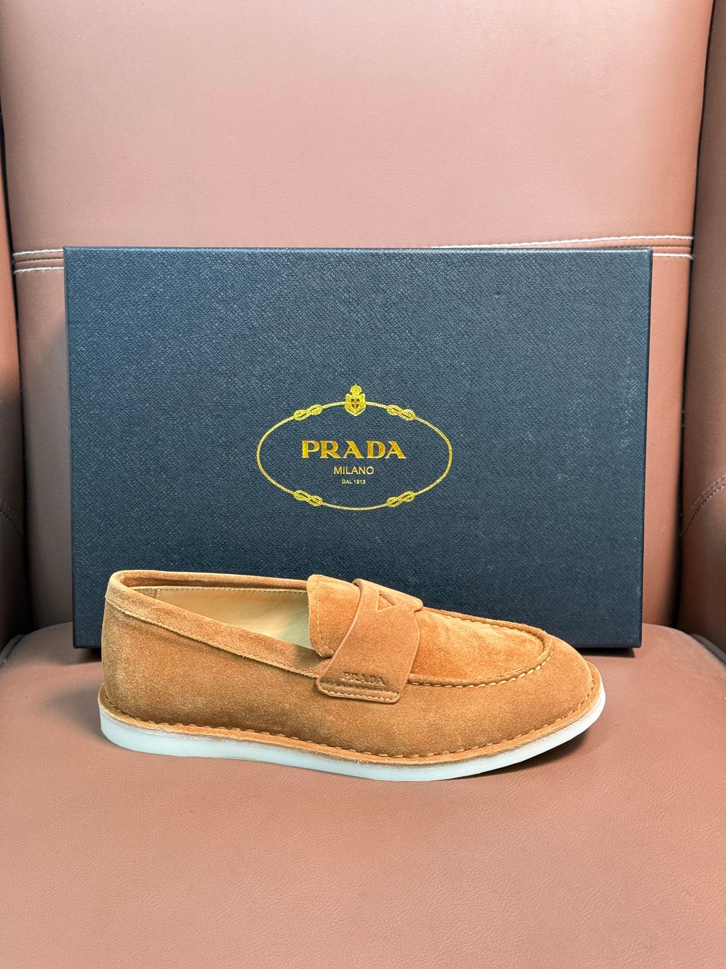 Prada unisex tan suede loafer with white rubber sole, boxed presentation.