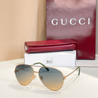 Gold-tone round sunglasses with light blue tinted lenses and green temple tips